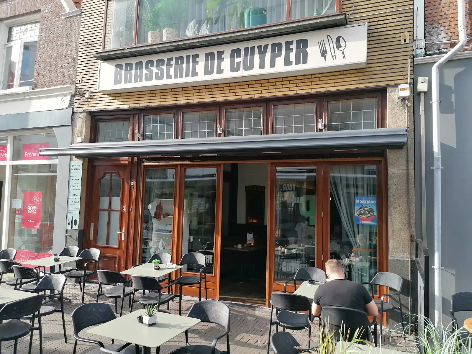 De gevel van Brasserie de Cuyper met het terras onder de markies op de Dracht
