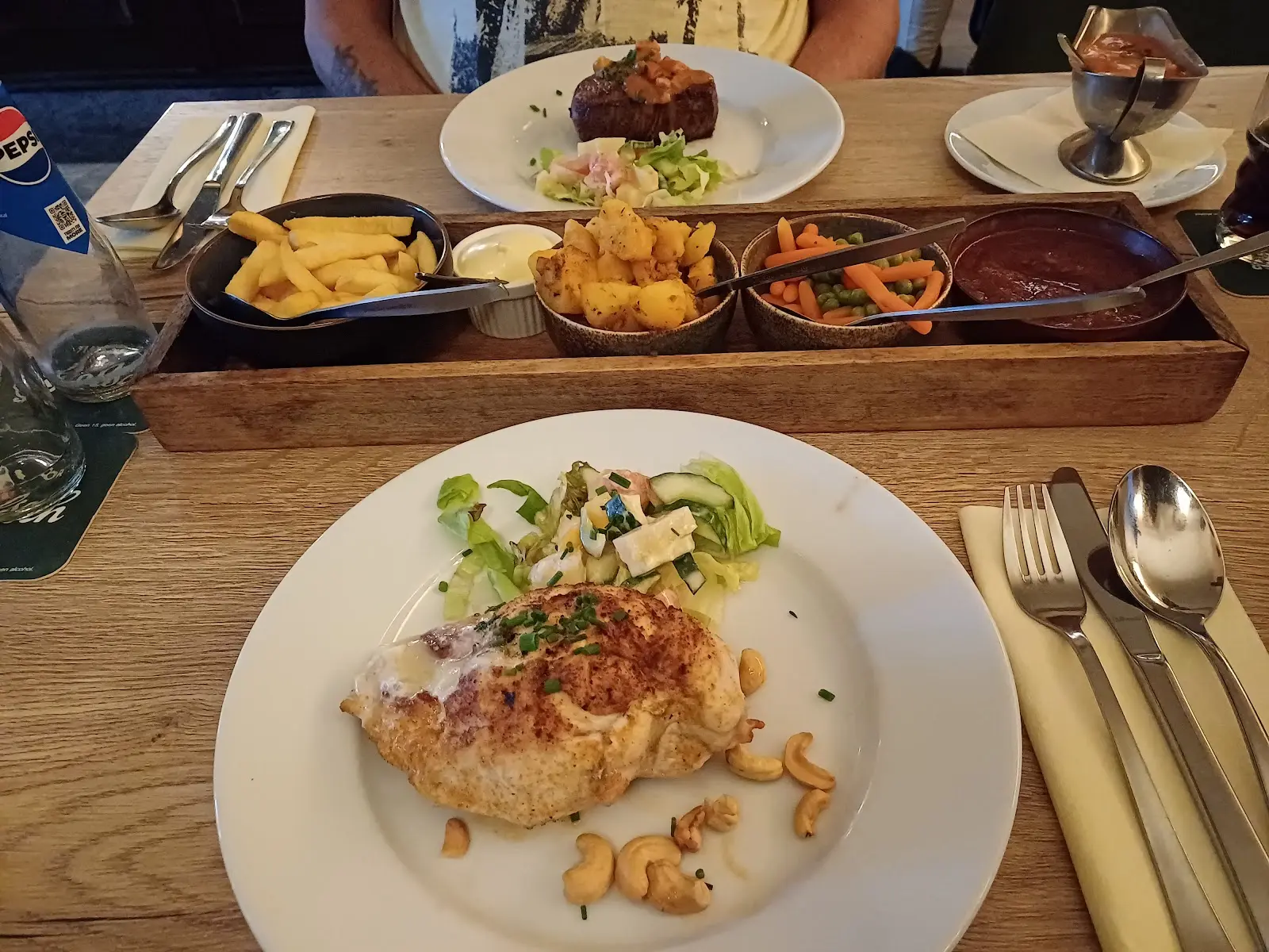 Kip met cashewnoten en salade, daarachter biefstuk en schaaltjes met friet, aardappeltjes, groente en saus